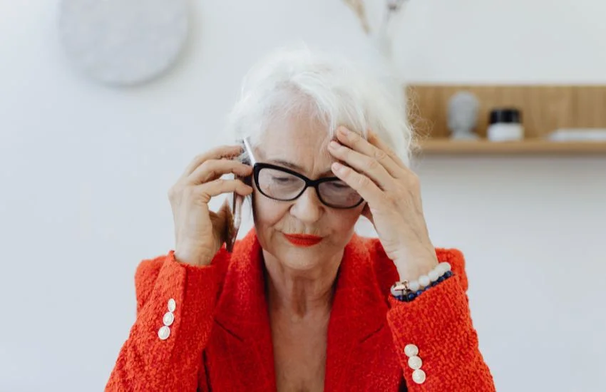 Mujer con gesto de molestia atiende el móvil por posibles llamadas spam.